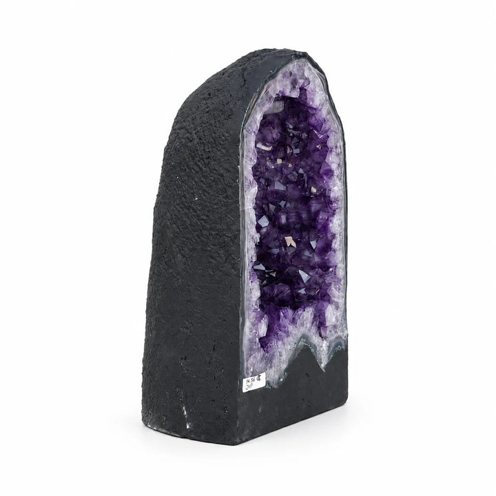 Sodriai violetinės spalvos ametisto kristalai geodoje su šviesos atspindžiais.