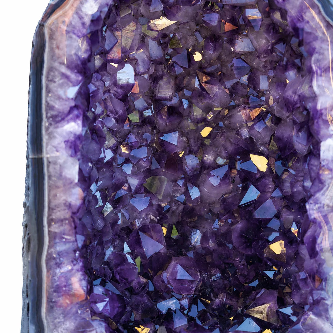 Sodriai violetinės spalvos ametisto kristalai geodoje su šviesos atspindžiais.